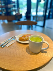 Serene morning coffee matcha tea latte with a delicious croissant in coffee shop. Peaceful start to the day in a cozy cafe. Enjoy the moment. Cozy ambiance, lifestyle enjoyment and morning routine