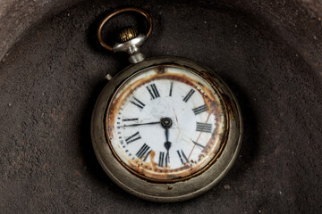Antique pocket watch at the bottom of an old ceramic container.