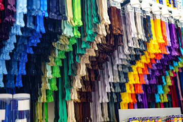 Colored sewing zippers for clothes of different colors close-up on the window display of a sewing...