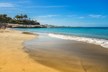 The gentle waves of Playa Del Duque in Tenerife reflect shades of turquoise and blue