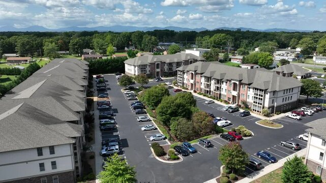 Aerial approaching shot of large upper class apartment houses in suburb district of Timberlake, Virginia, USA. Parking cars on street in front of houses and homes at sunlight.