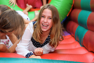 Cute girl in a colorful  inflatable bounce house. having fun at a children birthday party with kids...