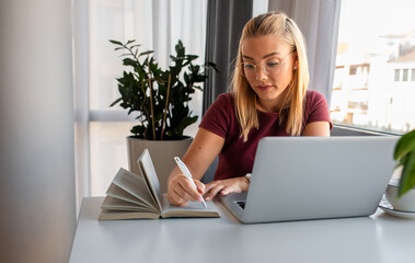 Fototapeta premium Woman sitting in office working using laptop.