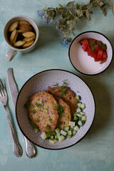 Golden zucchini pancakes on a blue plate, turquoise background, tinting. Sour cream sauce, vegetables.