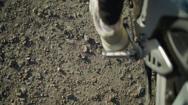 Close-up of a person s foot removing the kickstand from a motorcycle and pressing on the gear lever to move the bike forward