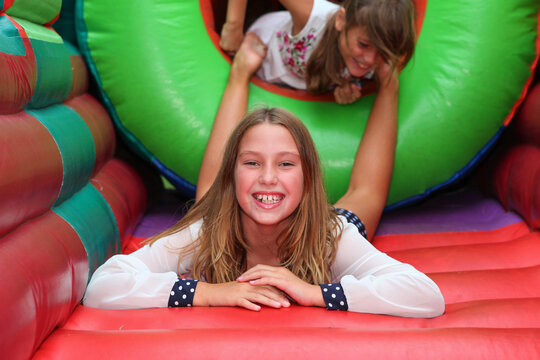 Cute girl in a colorful  inflatable bounce house. having fun at a children birthday party with kids in background