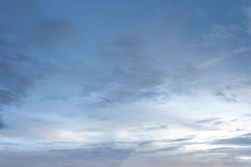 Dramatic cloudscape of white fluffy clouds against a deep blue sky, illuminated by the warm light of the setting sun