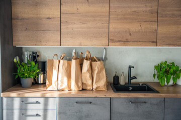 Paper bags full of food in home kitchen. Groceries ordered online and delivered by courier