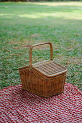 close-up of Red napkin and picnic basket. soft focus a Vintage wicker basket. Serene Picnic Moment: A Basket on Lush Green Grass. This captures the peaceful, relaxed atmosphere of a picnic scene.