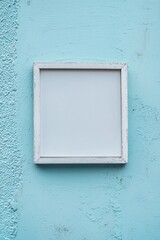 A pale blue wall with a whitewashed wooden frame, the blank center blending gently into the background 