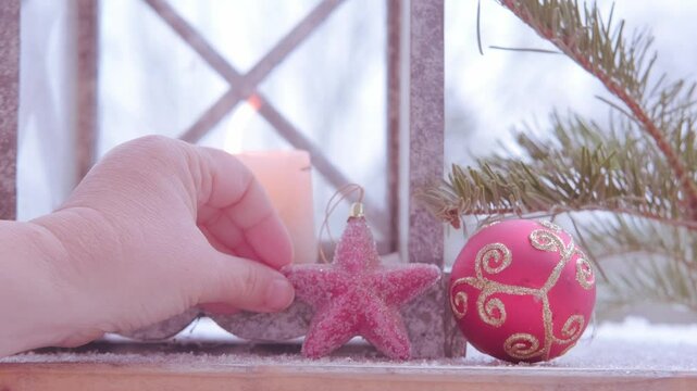 Christmas tree decoration, soft flame first Advent candle flickers inside garden lantern with snow gently falling in background for wintery feel, cozy Christmas scene