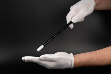 Hands in white glove with magical stick