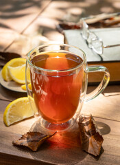 Cup of tea with lemon outdoors on wooden table