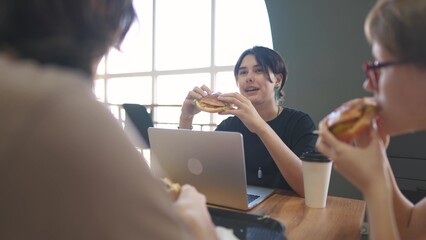 group of students sit in a cafe and do a project on a laptop together. business concept of modern...