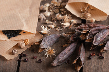 Seeds of garden flowers in small paper bags and glasses on wooden table