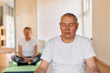 Obraz premium Close-up of a senior man deeply focused on meditation and relaxation during a yoga practice.