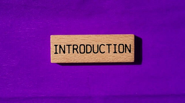Introduction message writing on wooden block on purple background. Conceptual introduction symbol.
