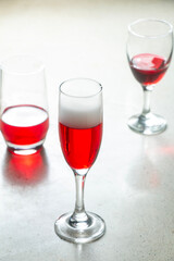 glass of Champagne Flute glass filled with red syrup and other types of glasses on terrazzo granite bar counter, red wine drink in glasses, drink party