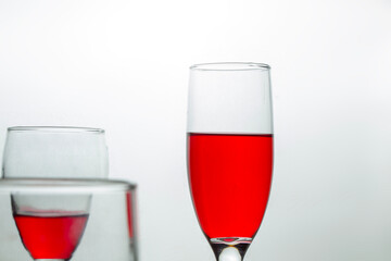 closeup of Champagne Flute glass filled with red syrup and part of another glass isolated on white, negative space