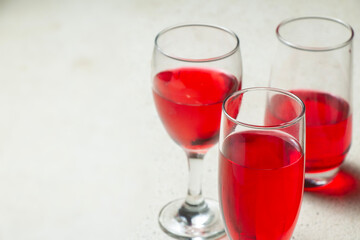negative space three wine bottles, tulip glasses, champagne glasses filled with red syrup inside on granite textured bar table, use text party bar