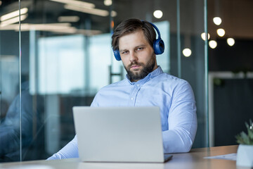 Focused Man with Headphones Working on Laptop at Office Desk