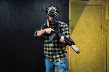 A man in civilian clothes practices tactical shooting with night vision and a rifle with a silencer...