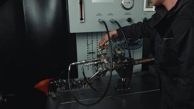 A car mechanic checks the tightness of a car steering rack under pressure in a specialized high-pressure test bench