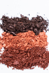 Scattered eye shadows in different shades. Cosmetics texture, white background.