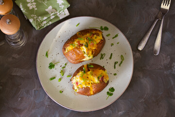 Cheesy stuffed baked potatoes topped with cheese, bacon and cream. Top view, flat lay