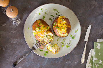 Cheesy stuffed baked potatoes topped with cheese, bacon and cream. Top view, flat lay