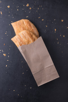 Two Jamaican beef patties in a brown paper bag against a black background