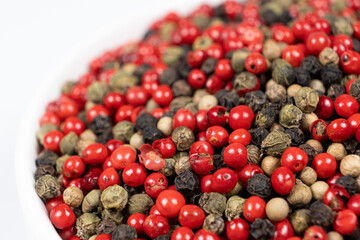 A mixture of different peppercorns on a white background