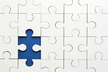 White puzzle with missing piece on blue background, top view