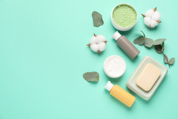 Different cosmetic products, leaves and cotton flowers on turquoise background, flat lay. Space for text