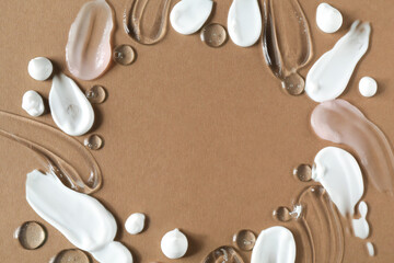 Frame of different cosmetic products smears on brown background, flat lay. Space for text