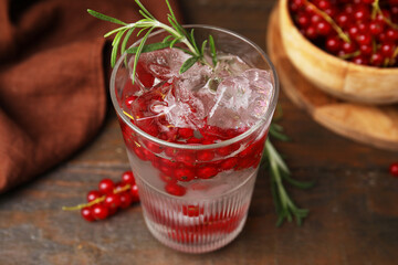 Refreshing water with red currants and rosemary in glass on wooden table, closeup