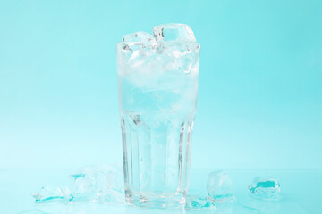 Refreshing water in glass with ice cubes on light blue background