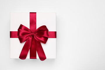 Gift box with red bow on light grey background, top view. Space for text