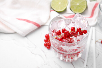Refreshing water with red currants in glass on light table, closeup. Space for text