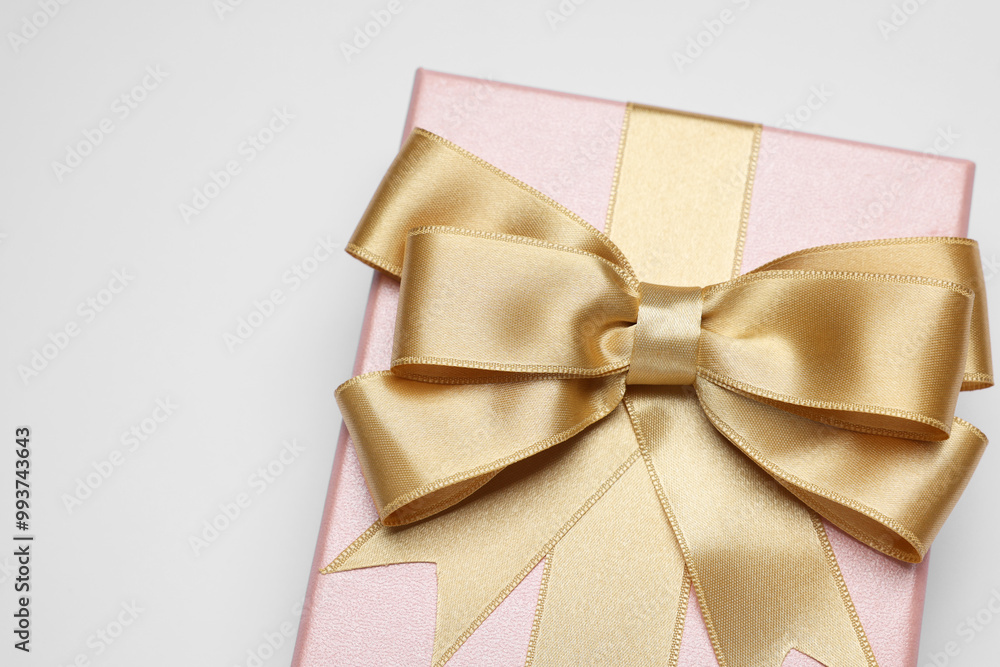 Poster Gift box with golden bow on light grey background, above view