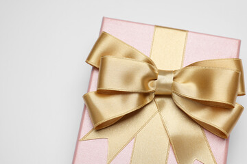 Gift box with golden bow on light grey background, above view