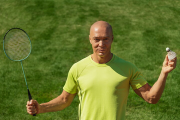 Man playing badminton on green sport court in public park. Outdoors. Summer sports game. Copy space. Close up.