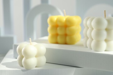 Beautiful bubble candles and geometric figures on table, closeup