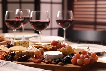Glasses of red wine and different snacks on table, selective focus