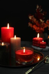 Beautiful burning candles and decor on black table, closeup