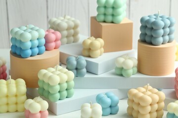Many beautiful bubble candles and podiums on white table