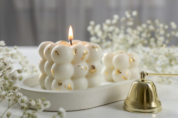 Stylish bubble candles, snuffer and gypsophila flowers on white wooden table, closeup