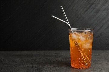 Tasty refreshing drink with straws in glass on grey textured table, space for text