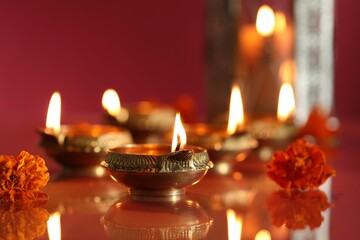 Diwali celebration. Diya lamps and beautiful flowers on color background, closeup