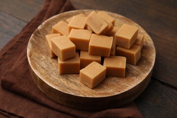 Tasty sweet caramel candies on wooden table, closeup